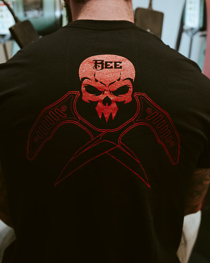 Back of black t-shirt with red skull and knives graphic, BEE text, gym setting