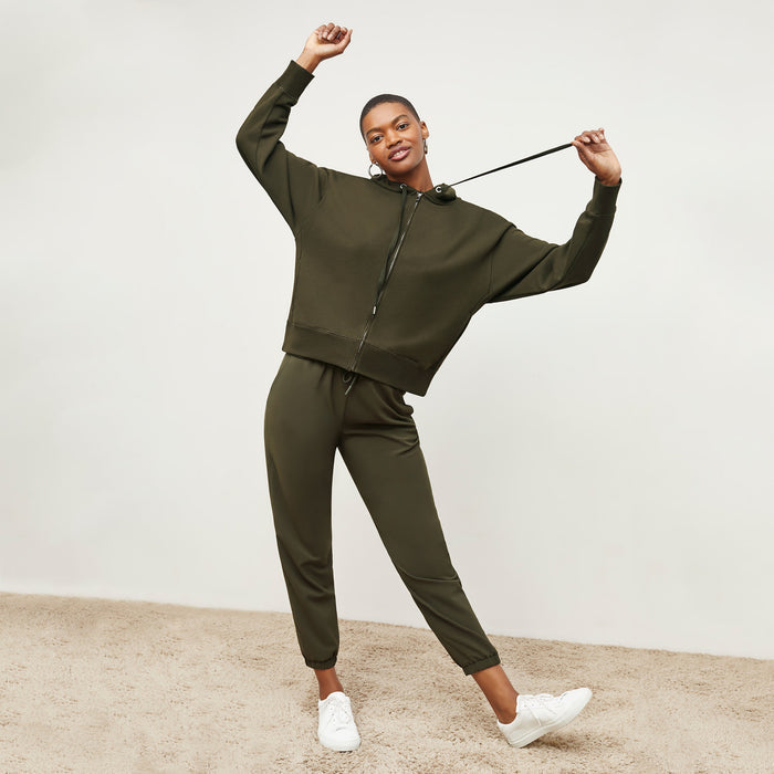 Front image of a woman standing wearing the Delaney Jogger—OrigamiTech in Olive | Lead