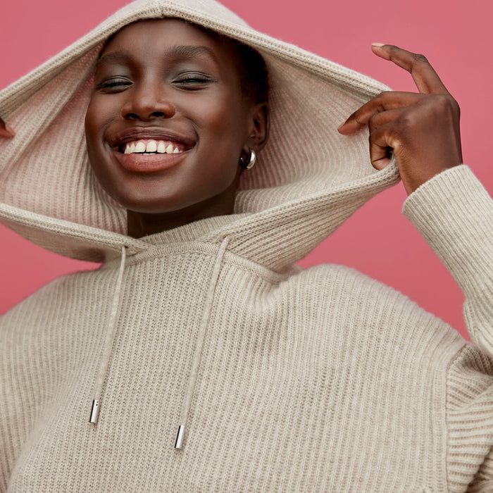 Front image of a woman standing wearing the Freya Hoodie—Cashmere/Wool in Oatmeal Melange