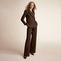Woman wearing a brown suit against a beige background | Lead