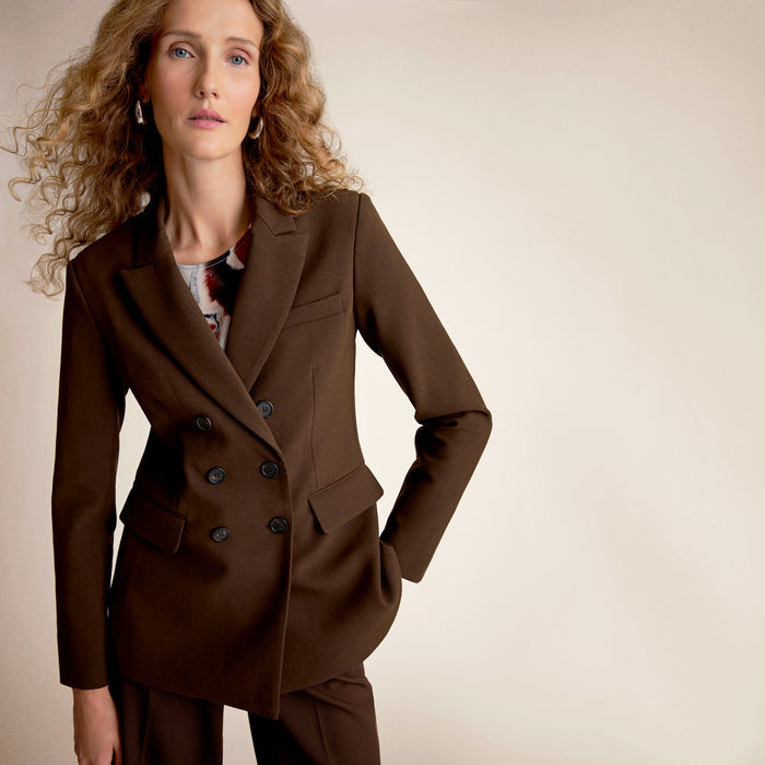 Woman wearing a brown coat against a beige background