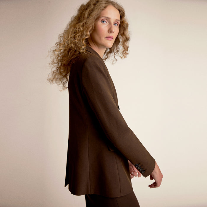 Woman wearing a brown suit against a beige background