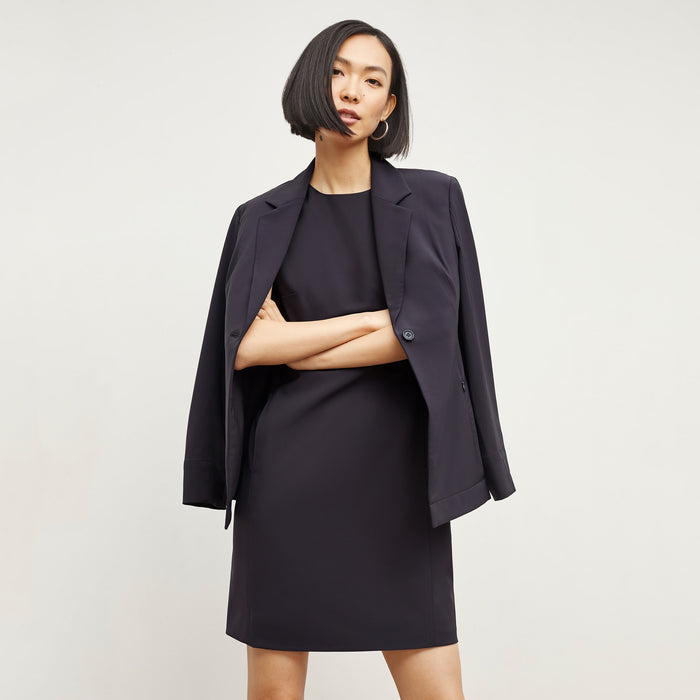 Front image of a woman standing wearing the Maaza Dress—Origami Suiting in Cool Charcoal