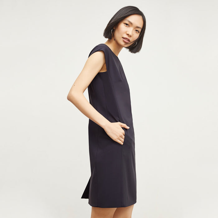 Side image of a woman standing wearing the Maaza Dress—Origami Suiting in Cool Charcoal