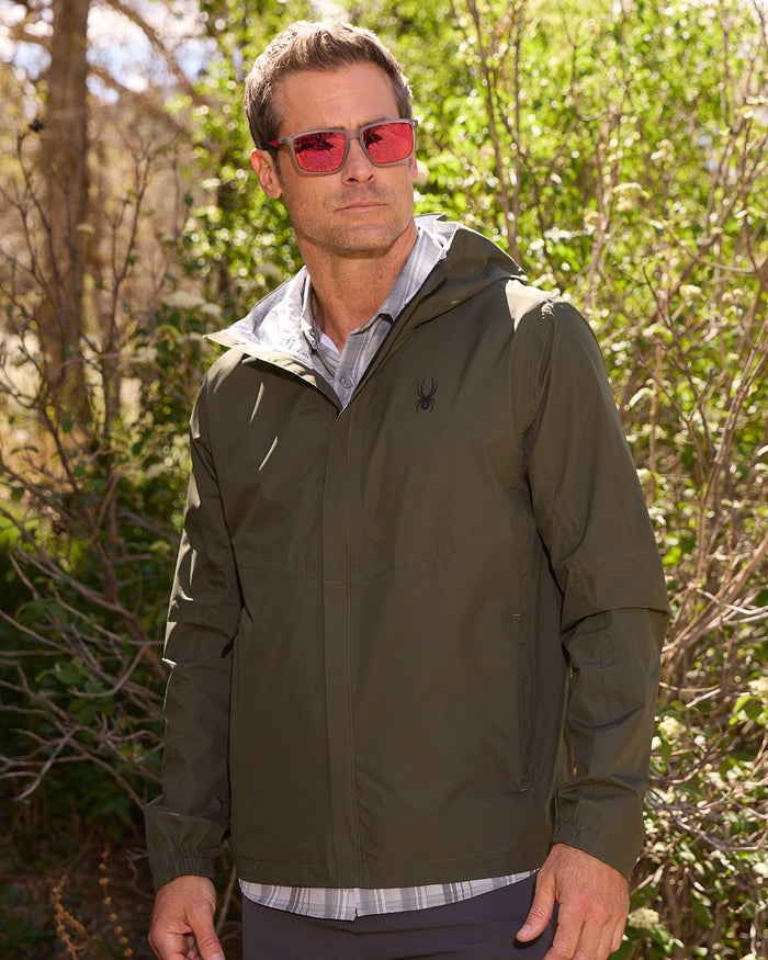 Man wearing a green jacket with a brand logo outdoors
