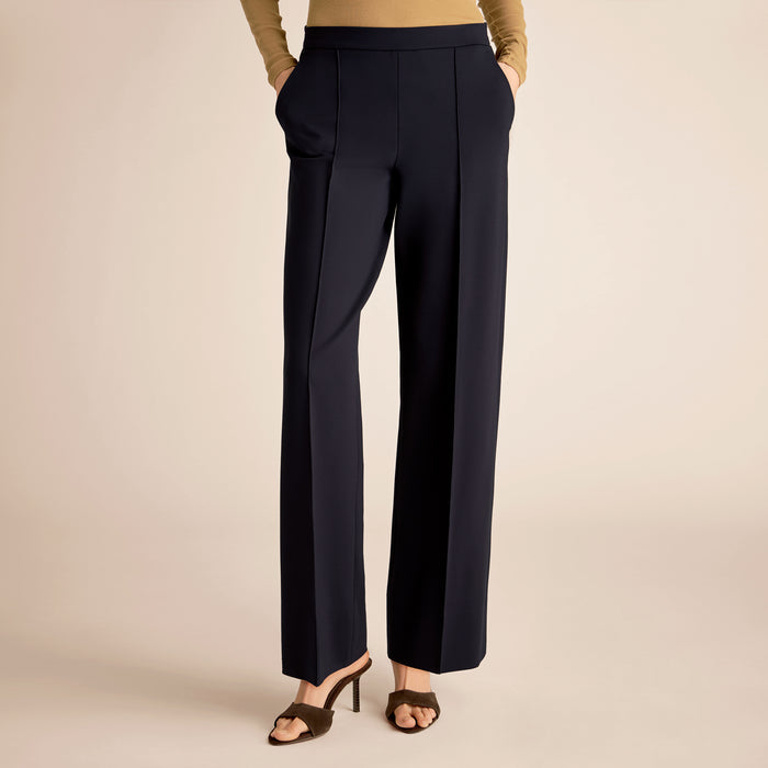 Navy blue pants worn by a person on a beige background | Lead