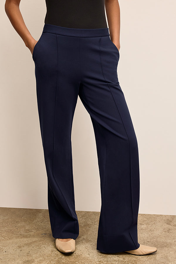 Navy blue pants worn by a person on a beige background | Exclude