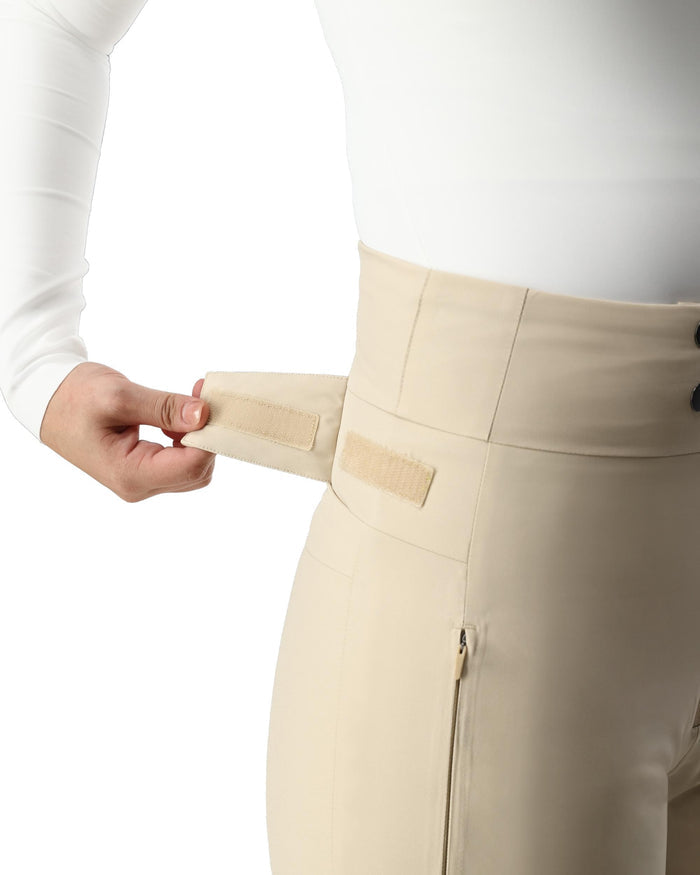 Person wearing beige pants with a white shirt, adjusting a beige patch on the waistband.