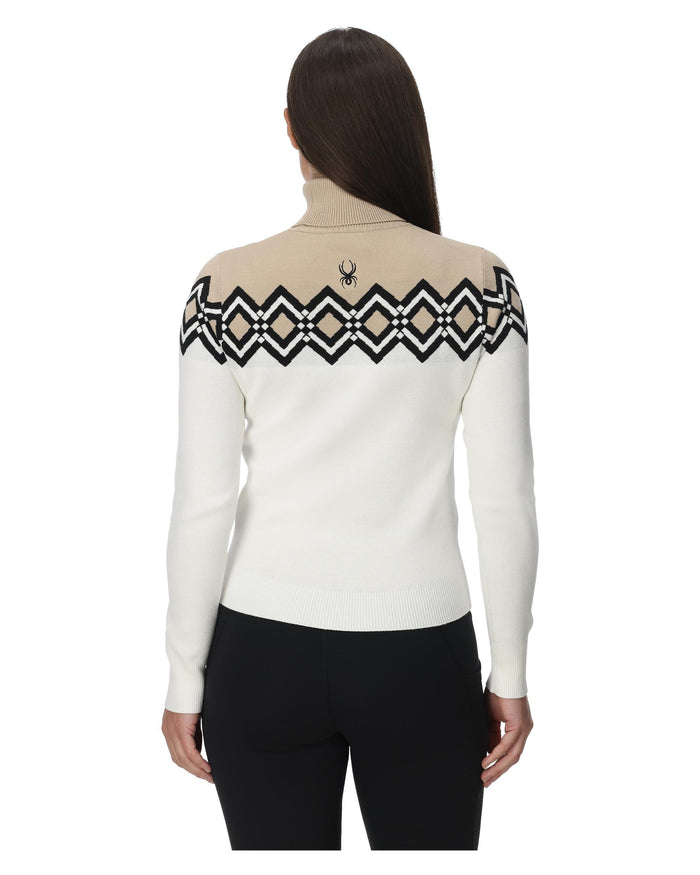 Woman wearing a white sweater with black geometric patterns on a white background