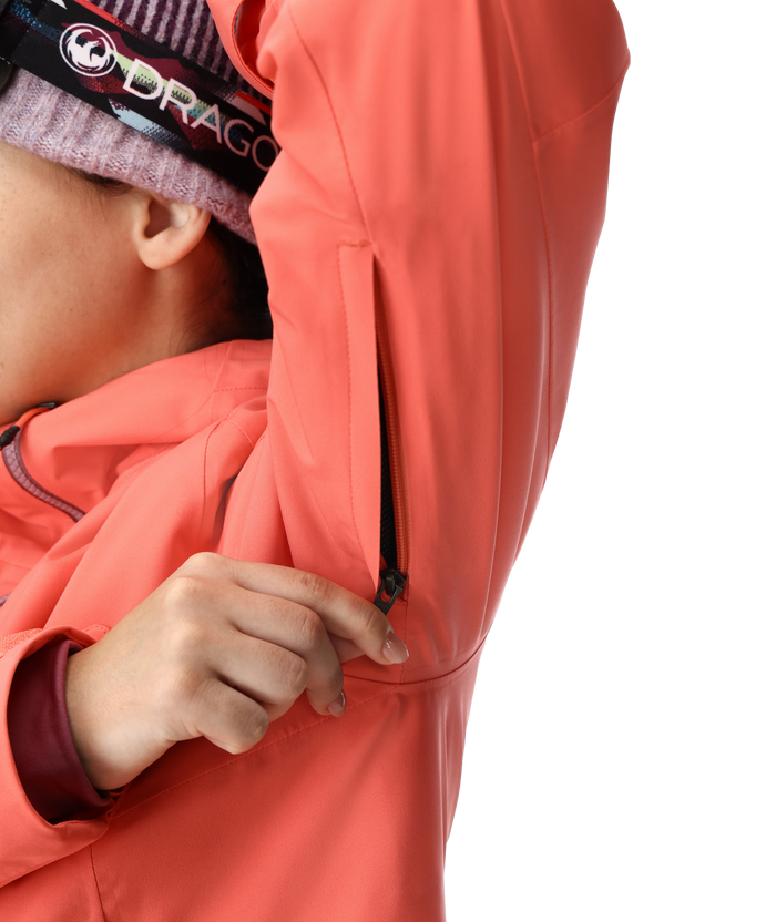 Person wearing a coral jacket with a brand logo on a white background